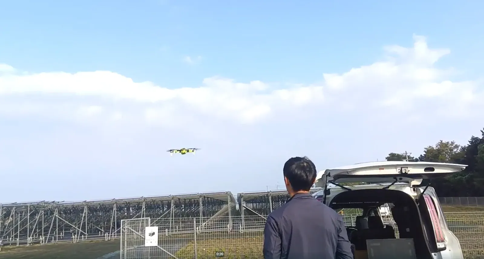 太陽光発電所で作業車のそばからドローンを操縦するオペレーター